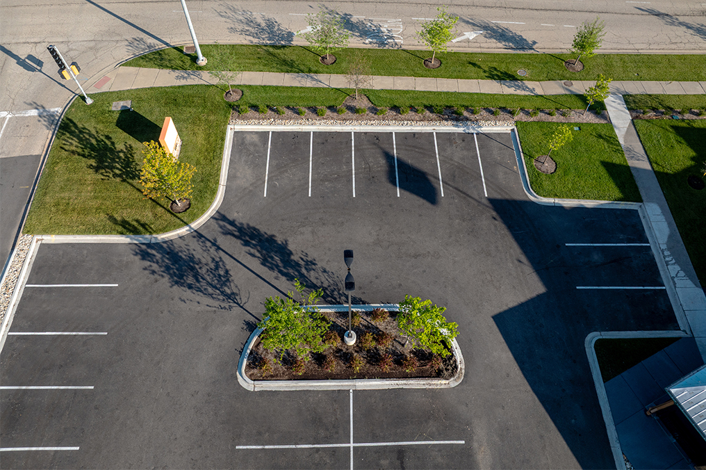 Drone image above Ashley Furniture and Texas Roadhouse showcasing landscape and parking lot renovated by Corebuilt Contracting