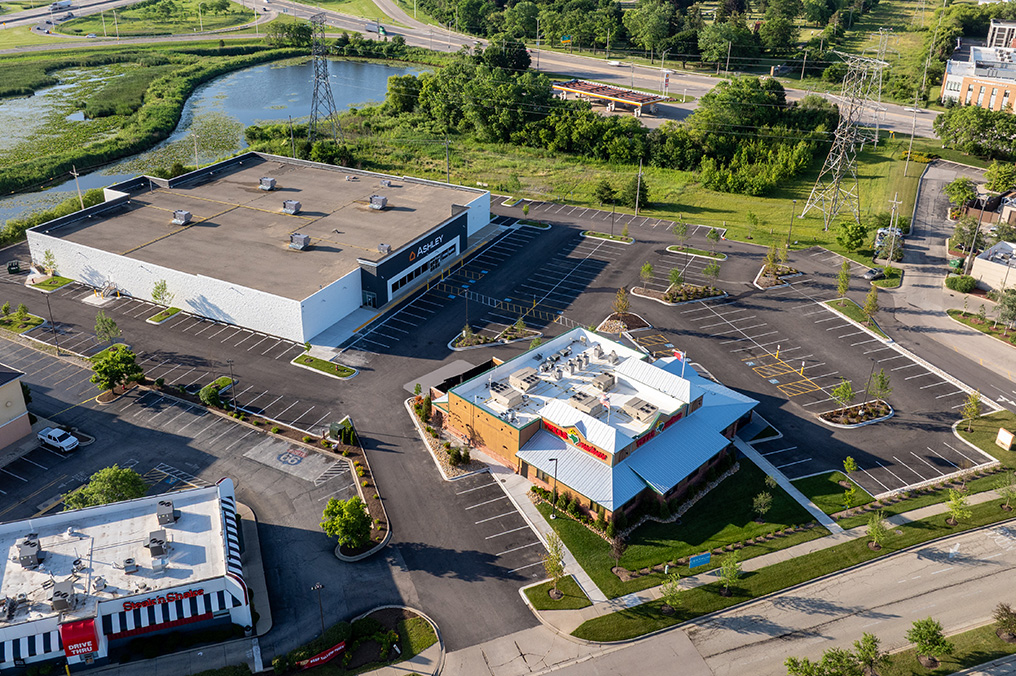 Drone image above Ashley Furniture Homestore and Texas Roadhouse near Gurnee Mills parking lot renovated by Corebuilt Contracting with landscape plan and green grass in Gurnee Illinois